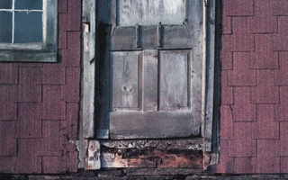 A brown barn door with red shingles on the side.