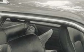 A child lies in the backseat of a car.