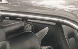 Brown-tinted print of a child lying down in the backseat of a car.