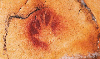 Pigment print of a handprint on an orange cave wall.