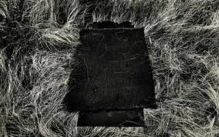 A square of dark fabric laid on top of grass.