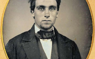 Top-half portrait of a man dressed in a dark suit.