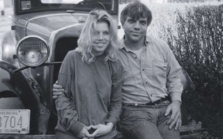 A man and woman sitting together on the front of a car.