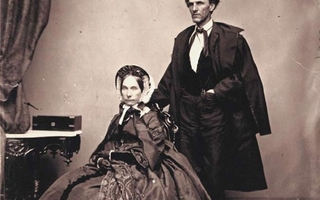 Brown-tinted print of a man standing in a dark suit and a woman sitting in a dress.