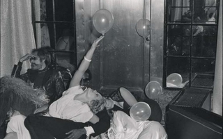 A woman reaches up towards a balloon inside while lying among a group of people.