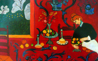 A maid arranging a display of fruit on a red table in a red room.