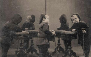 Children in dark clothing leaning against small seats.