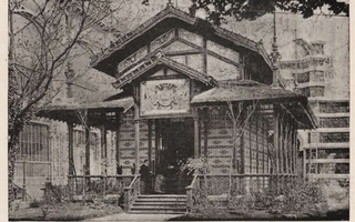 View of a house with a man sitting on the porch.